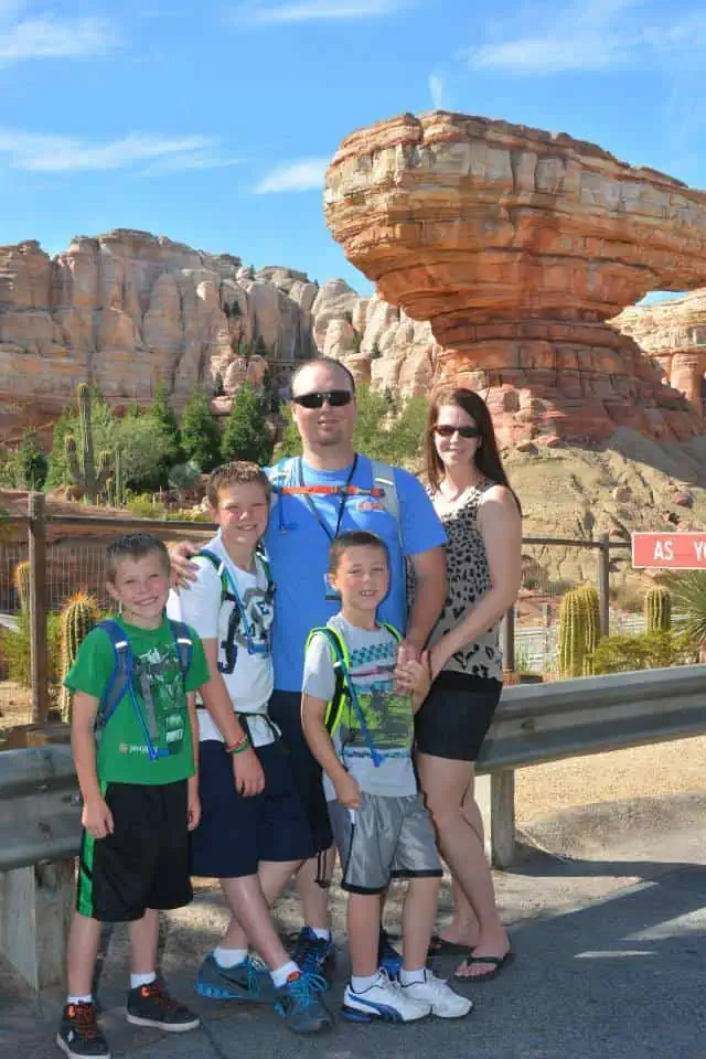 Photo of Jesse L. with his wife and three sons in front of Radiator Springs Racers at Disney California Adventure — Jesse has his arms around two of the boys, and the family is smiling and enjoying their time together.