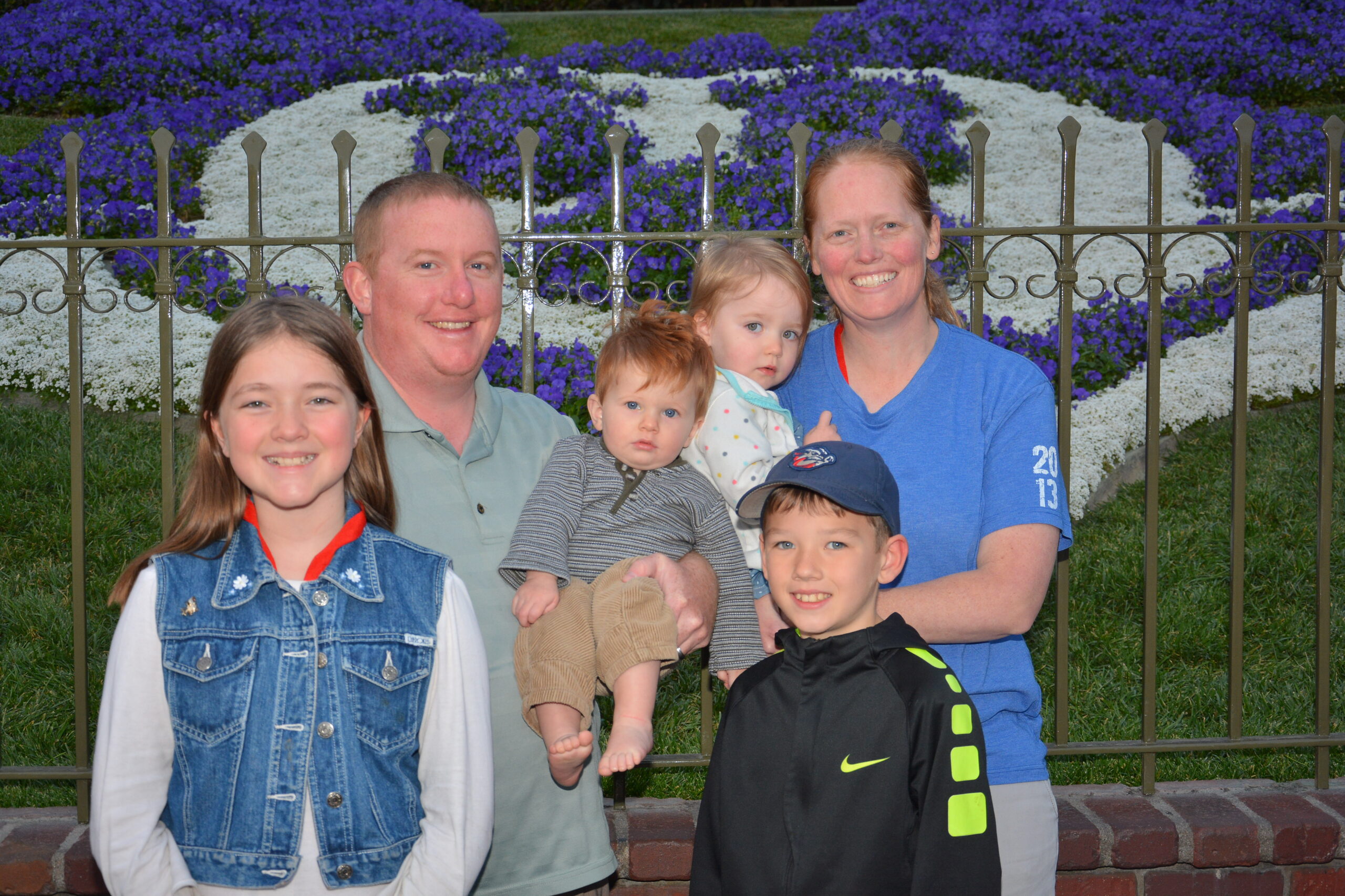 Will S. Family smiling in front of Floral Mickey in Disneyland California
